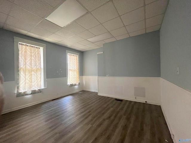 empty room featuring a drop ceiling and dark hardwood / wood-style flooring