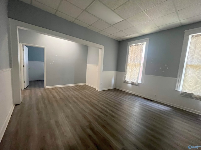 spare room with a drop ceiling and dark hardwood / wood-style floors