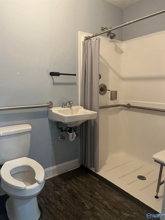 bathroom featuring walk in shower, sink, hardwood / wood-style floors, and toilet