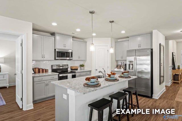 kitchen with baseboards, gray cabinets, tasteful backsplash, a sink, and appliances with stainless steel finishes