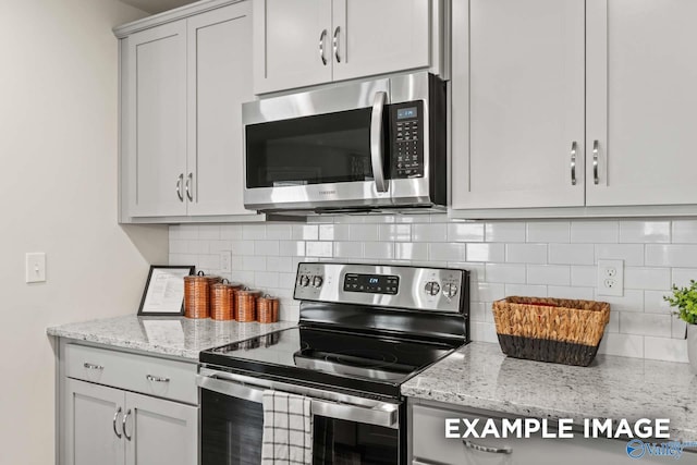 kitchen with light stone counters, backsplash, and stainless steel appliances
