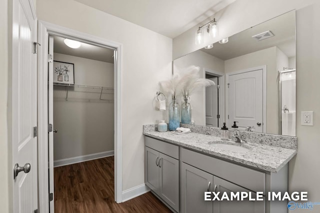 full bathroom featuring baseboards, vanity, wood finished floors, and visible vents