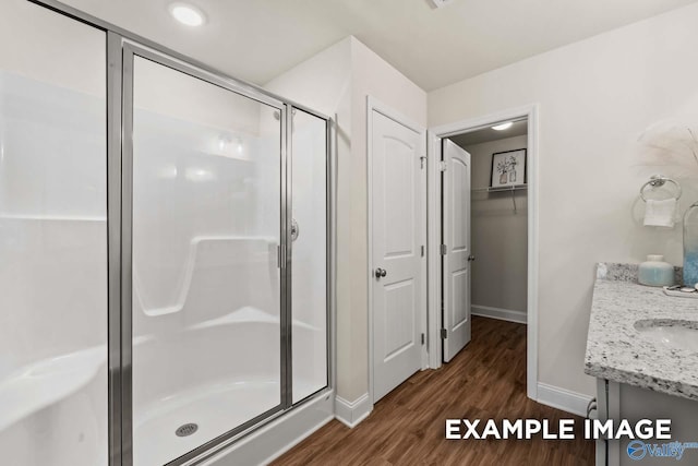 full bathroom featuring baseboards, a shower stall, wood finished floors, and vanity
