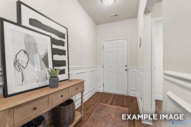 entryway with a wainscoted wall, a decorative wall, dark wood-style flooring, and visible vents