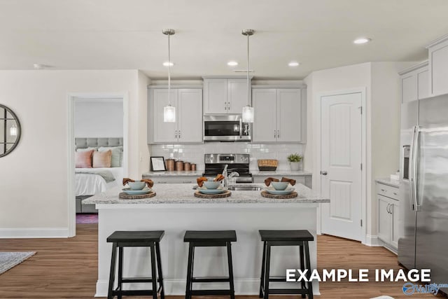 kitchen with appliances with stainless steel finishes, wood finished floors, and a breakfast bar