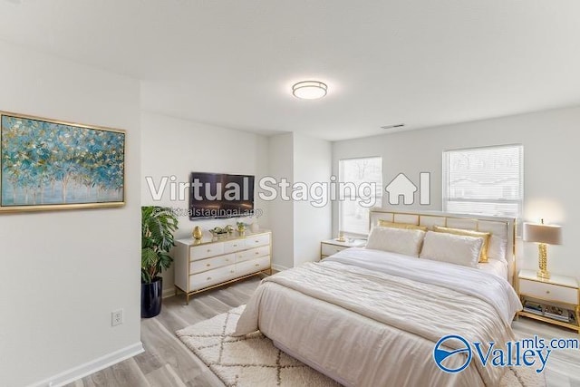 bedroom with wood finished floors, visible vents, and baseboards