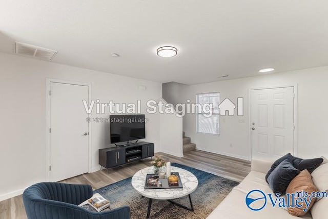 living area with baseboards, visible vents, stairway, and wood finished floors