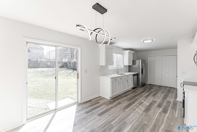 kitchen with light countertops, appliances with stainless steel finishes, a sink, and a wealth of natural light