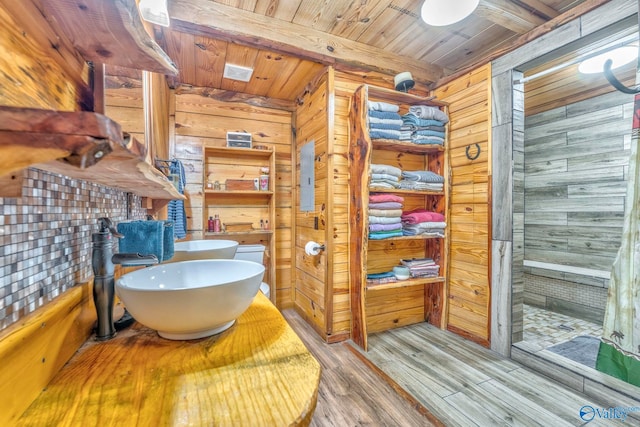 bathroom featuring wood ceiling, wood walls, hardwood / wood-style floors, beamed ceiling, and sink