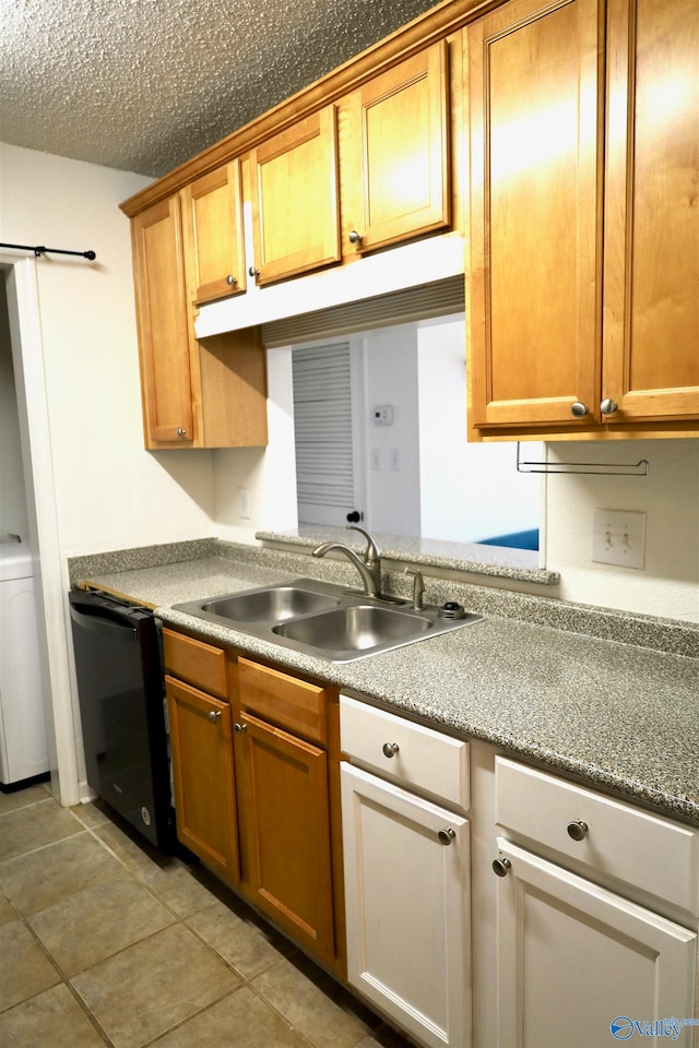 kitchen featuring light tile patterned flooring, sink, dishwasher, washer / dryer, and a textured ceiling