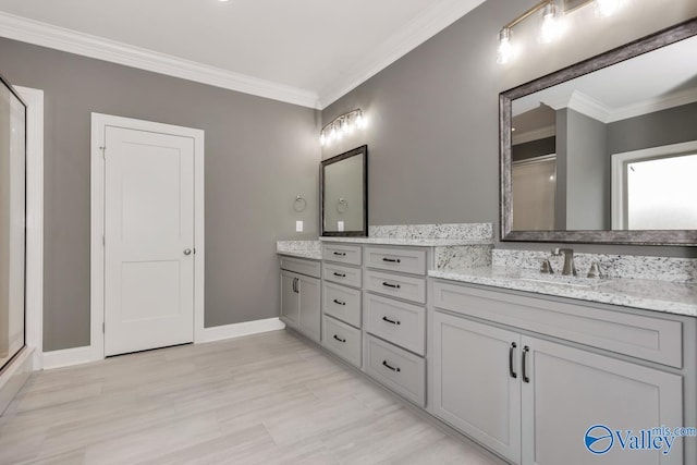 full bath with double vanity, a sink, crown molding, and baseboards