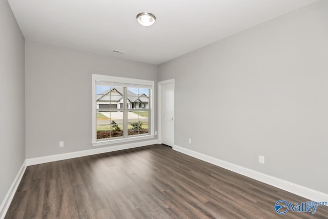 unfurnished room featuring dark wood-type flooring, baseboards, and visible vents