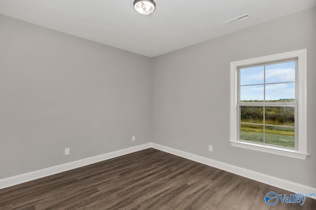 empty room featuring dark wood-style floors, baseboards, and visible vents