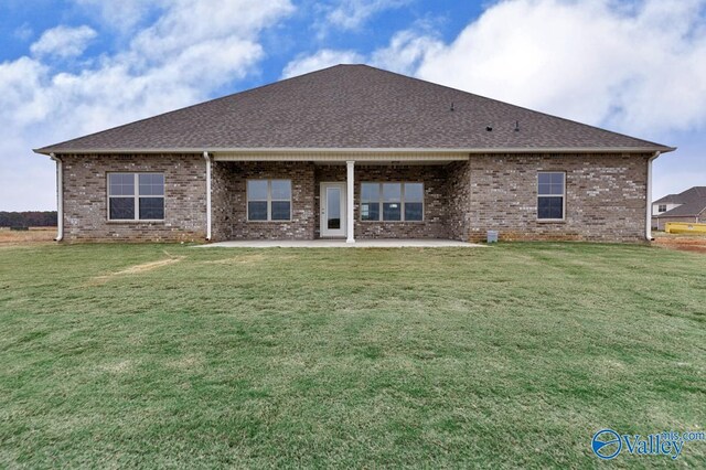back of house with brick siding, a lawn, and a patio