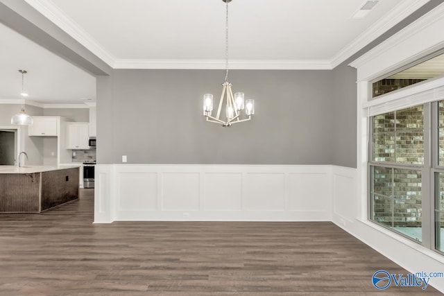 unfurnished dining area with crown molding, an inviting chandelier, sink, and wood-type flooring