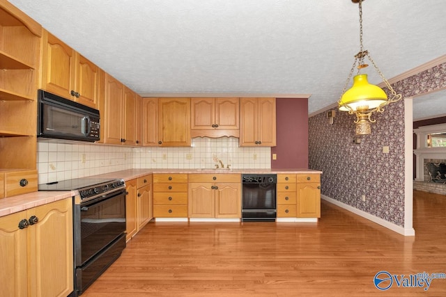 kitchen with tile countertops, wallpapered walls, open shelves, a sink, and black appliances