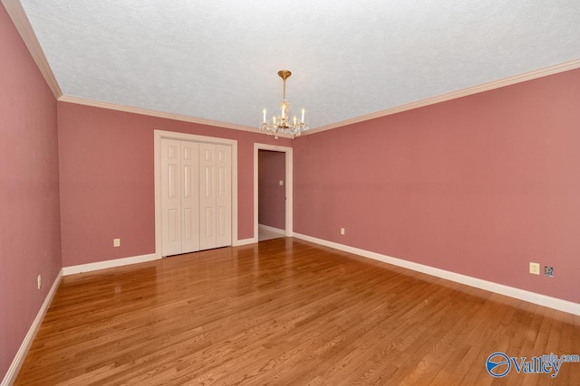 interior space with wood finished floors, baseboards, ornamental molding, a closet, and a notable chandelier