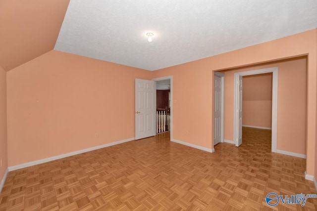 empty room with vaulted ceiling, baseboards, and a textured ceiling