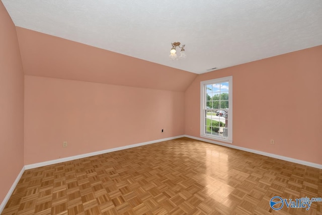 bonus room with a textured ceiling, lofted ceiling, and baseboards