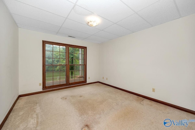 empty room featuring baseboards, a drop ceiling, and carpet floors