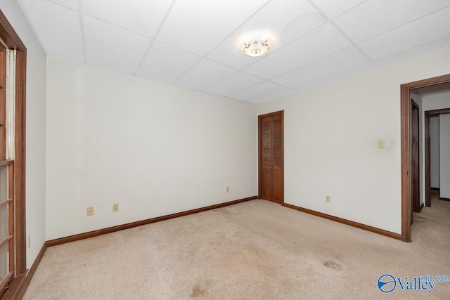 empty room featuring carpet, baseboards, and a drop ceiling