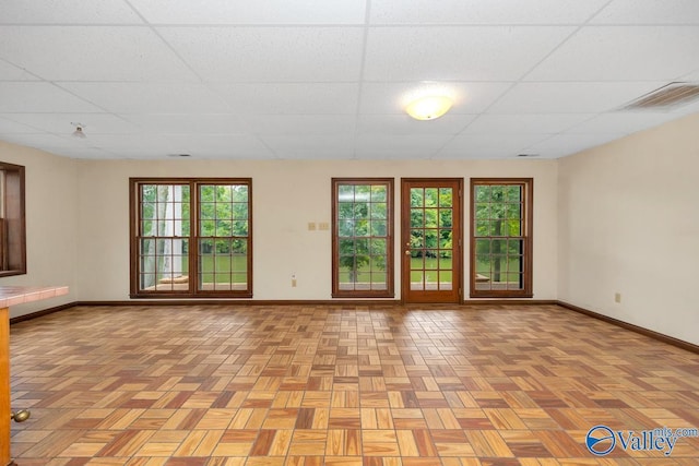 unfurnished room with a paneled ceiling, visible vents, and baseboards