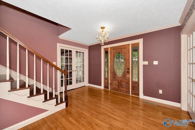 entryway with wood finished floors, stairway, french doors, baseboards, and a chandelier