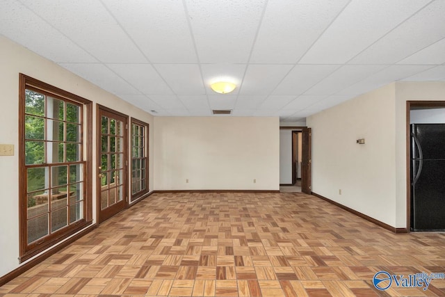 spare room with visible vents, baseboards, and a drop ceiling