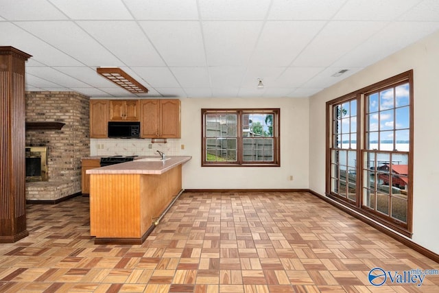 kitchen featuring visible vents, baseboards, light countertops, a peninsula, and black appliances