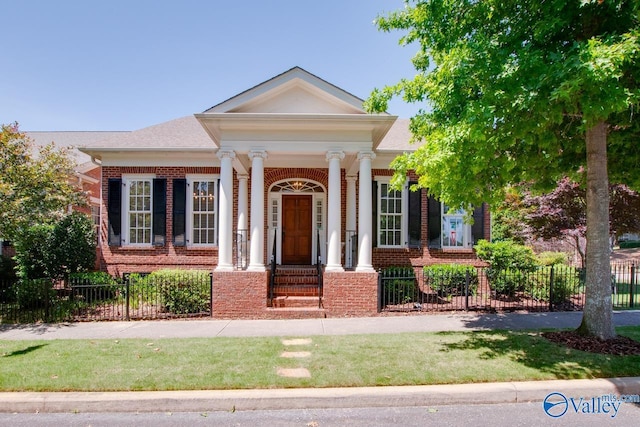 neoclassical / greek revival house with a fenced front yard, brick siding, and a porch