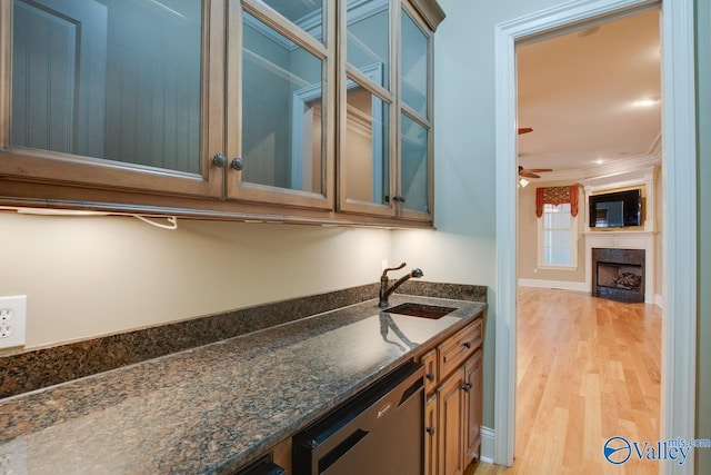 bar featuring a sink, a fireplace, crown molding, stainless steel dishwasher, and light wood-style floors