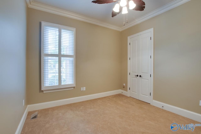 unfurnished room with ceiling fan, carpet, visible vents, and ornamental molding