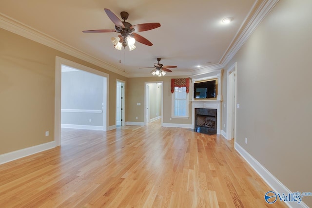 unfurnished living room with ceiling fan, crown molding, a large fireplace, baseboards, and light wood-style floors