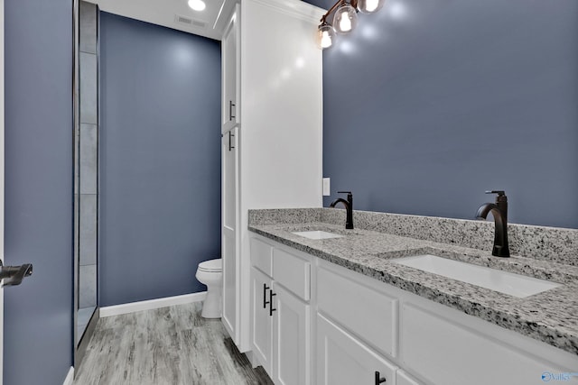 bathroom featuring walk in shower, toilet, wood-type flooring, and dual bowl vanity