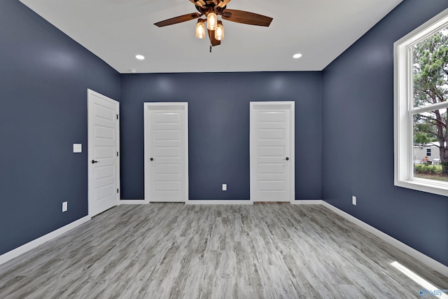 unfurnished bedroom with multiple windows, ceiling fan, and light wood-type flooring