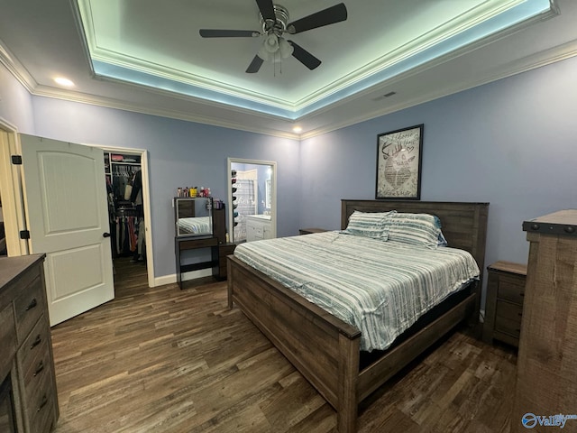 bedroom with a raised ceiling, ceiling fan, dark hardwood / wood-style floors, a spacious closet, and a closet