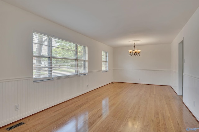 unfurnished room featuring a notable chandelier and light hardwood / wood-style flooring