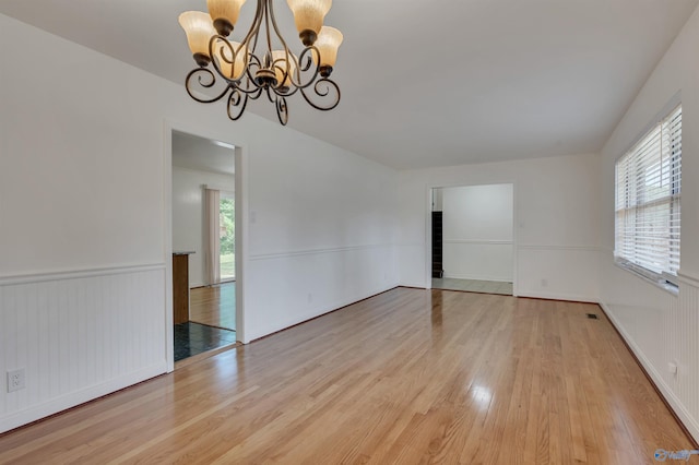 empty room with light hardwood / wood-style flooring and a chandelier