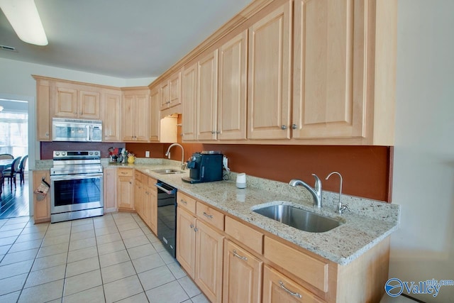 kitchen with light brown cabinets, appliances with stainless steel finishes, light stone counters, and a sink