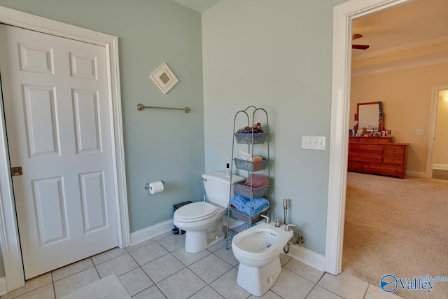 bathroom with baseboards, toilet, a bidet, ornamental molding, and tile patterned floors