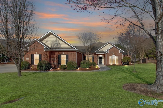 view of front of property with brick siding and a yard