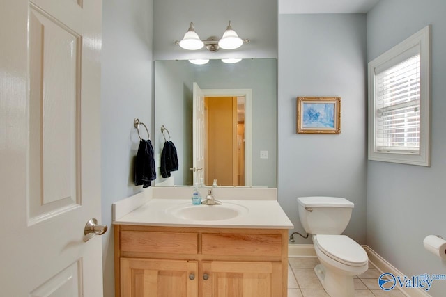 half bathroom featuring tile patterned flooring, toilet, vanity, and baseboards