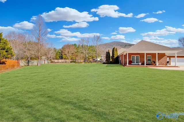 view of yard featuring french doors, a mountain view, and fence