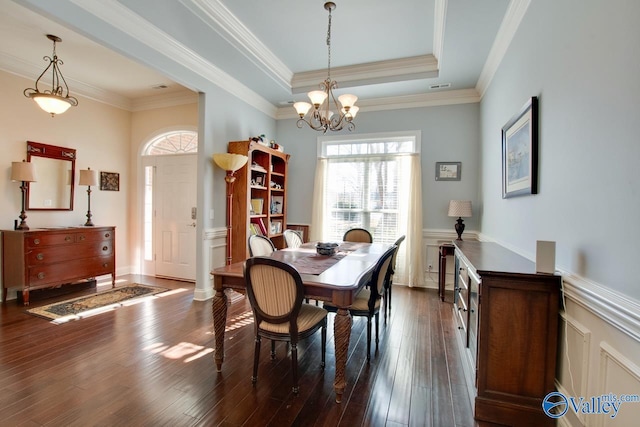 dining area featuring dark wood-style floors, a wainscoted wall, crown molding, and a tray ceiling