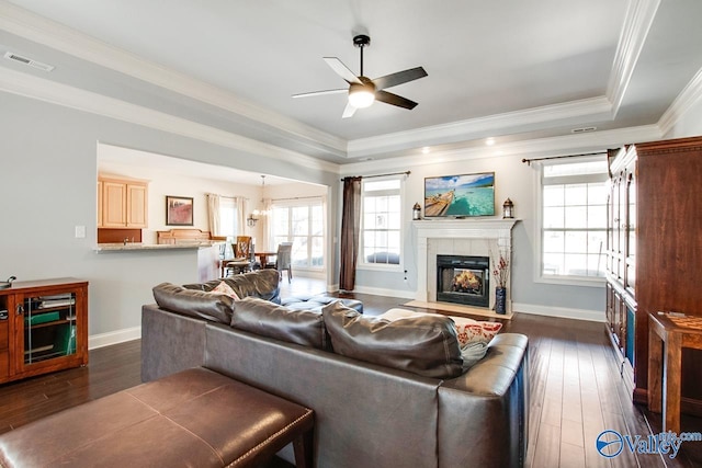 living room with a tray ceiling, a healthy amount of sunlight, and dark wood finished floors