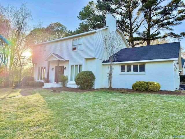 view of front of home featuring a chimney, a front lawn, and brick siding