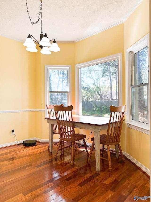 dining area with crown molding, wood finished floors, a textured ceiling, baseboards, and an inviting chandelier