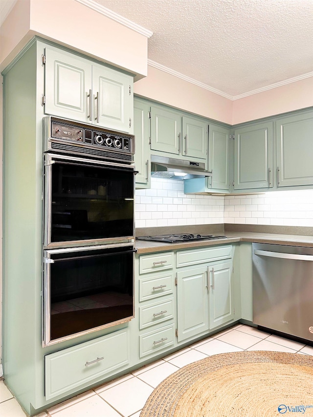 kitchen featuring decorative backsplash, crown molding, under cabinet range hood, black appliances, and light tile patterned floors