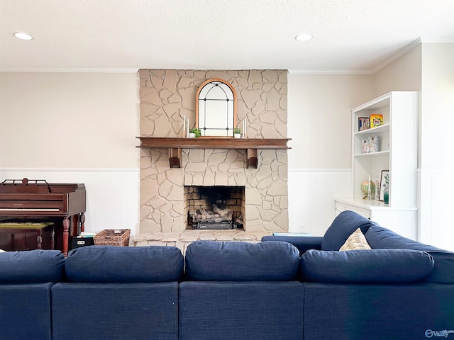 living area with a textured ceiling, a wainscoted wall, ornamental molding, and a fireplace