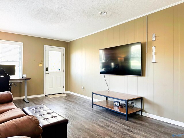 living room with baseboards, a textured ceiling, wood finished floors, and crown molding